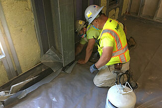 College of the Holy Cross - Construction Process Two construction workers install REGUPOL acoustics products around a steel beam in the College of the Holy Cross Recreation and Wellness Center.