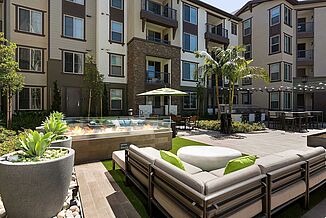 Patio area, featuring a fire pit, artificial turf and palm trees at Avalon Bay Communities in Glendora.