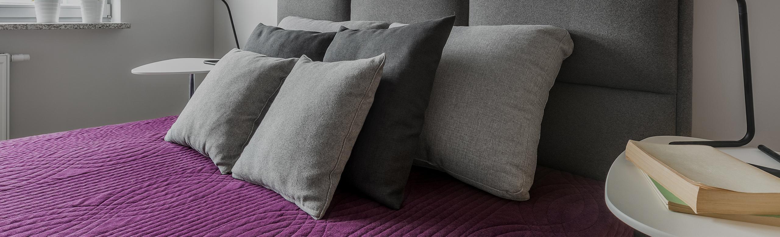 A bed in a hotel room that features REGUPOL acoustics for noise absorption.When choosing city hotels, a central location, amenities, and quiet, clean rooms are important. Our REGUPOL sonus range offers noise reduction solutions for construction needs. 