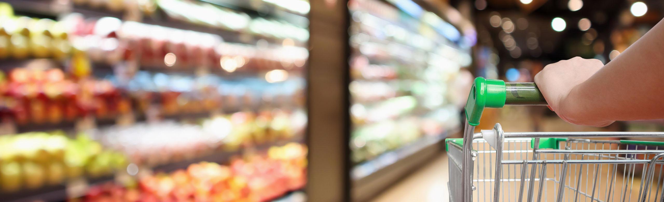 A shopping trolley is pushed through a supermarket.